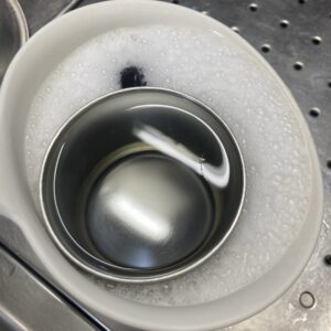 ステンレスのマグカップを、酸素系漂白剤を溶いたお湯につけ置き洗いしている写真。