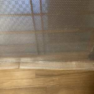 ガラス障子にプチプチを貼り、丈を切らずに谷折りにして隙間風を防いでいる写真